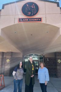 Eileen Holden stands at center with Dee Anne Taylor to her right inside Clark County Jr./Sr. High School. Both staff members smile, representing their multiple roles at the school.