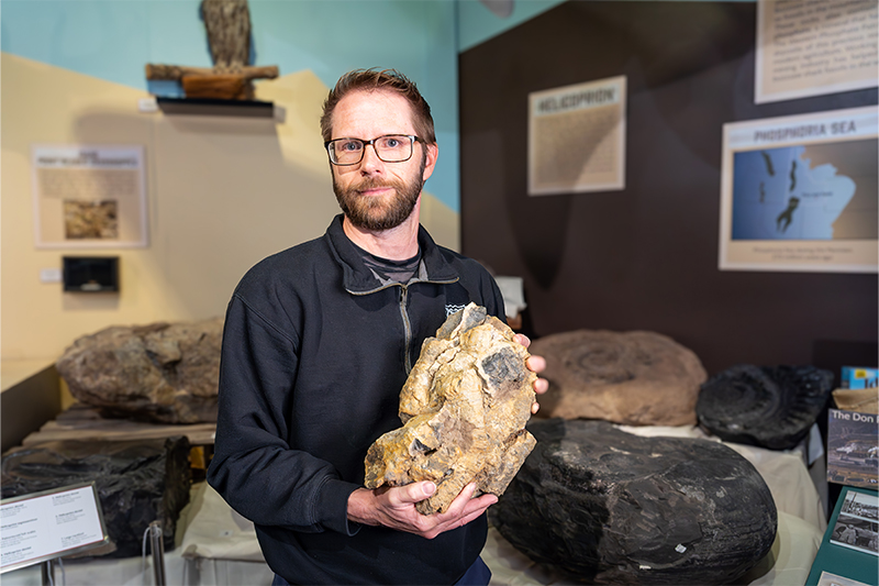 Leif Tapanila, director of the Idaho Museum of Natural History and professor of geosciences at Idaho State University, poses for a photo holding a piece of chert containing spicules.
