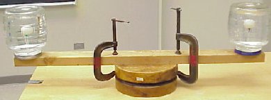 A rotating platform with jars on each side. Ping Pong balls on water in the jars.