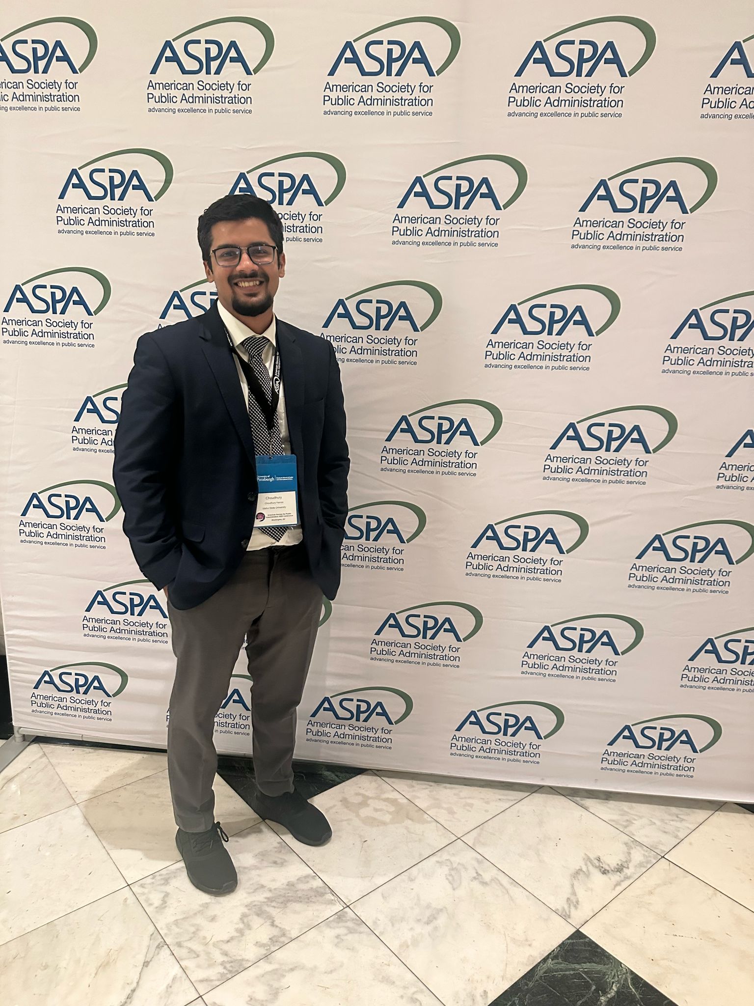 Student stands smiling in front of white background in business casual