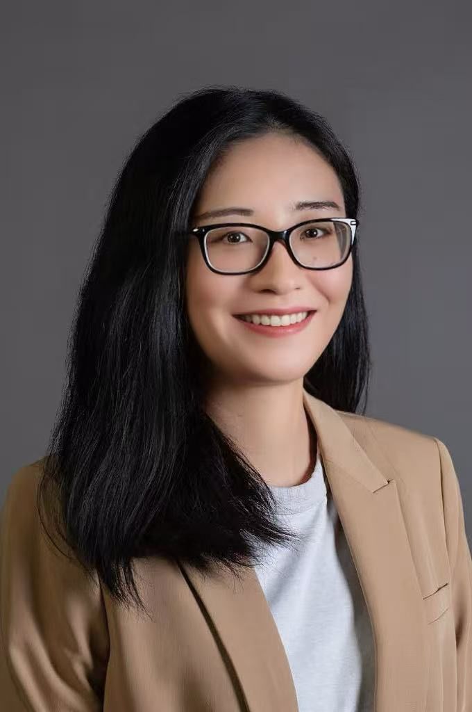 Headshot of Asian woman with glasses and tan blazer with gray background