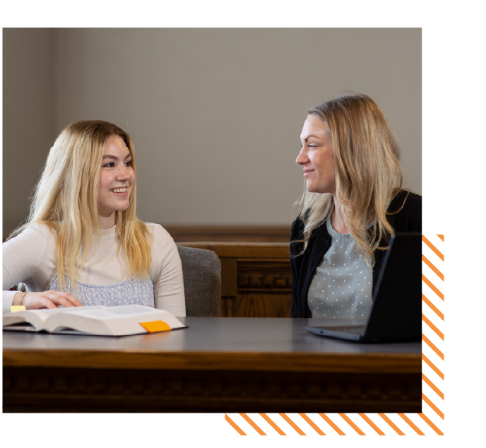 Graduate student and faculty member seated at a table reviewing coursework and discussing academic goals, representing advanced study and personalized mentorship in ISU’s graduate degree programs.