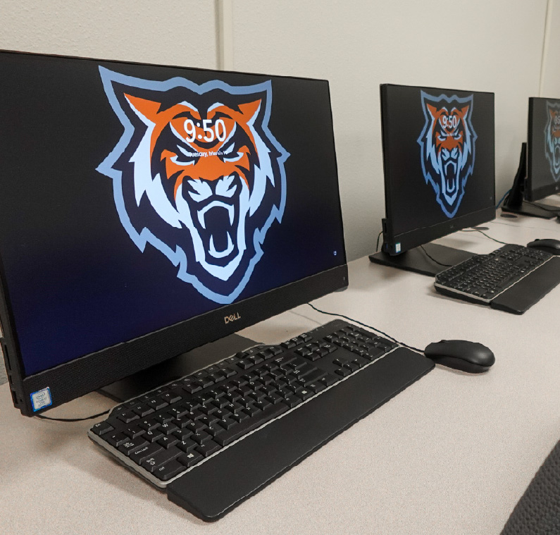 A row of desktop computers in a campus lab, each displaying an Idaho State Bengals logo on the screen, with keyboards and mice arranged neatly on the desks.