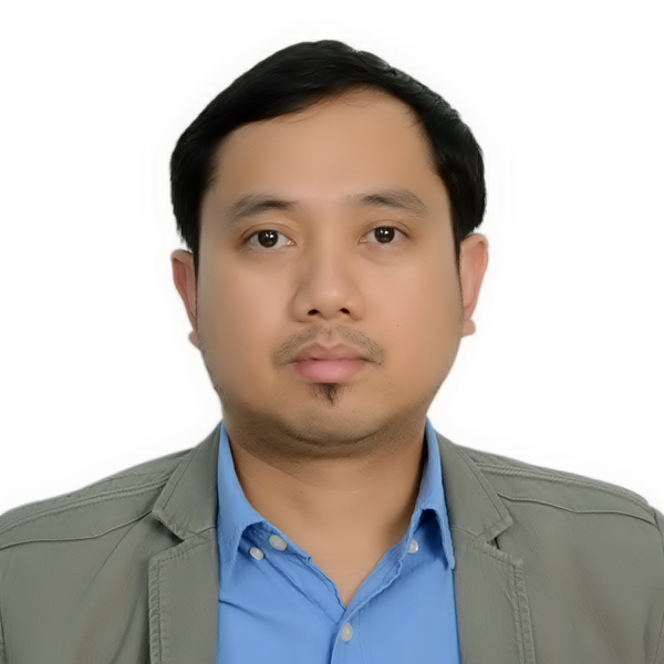 A medium skin toned man with black hair and beard. He is wearing a blue shirt with a grey suit jacket