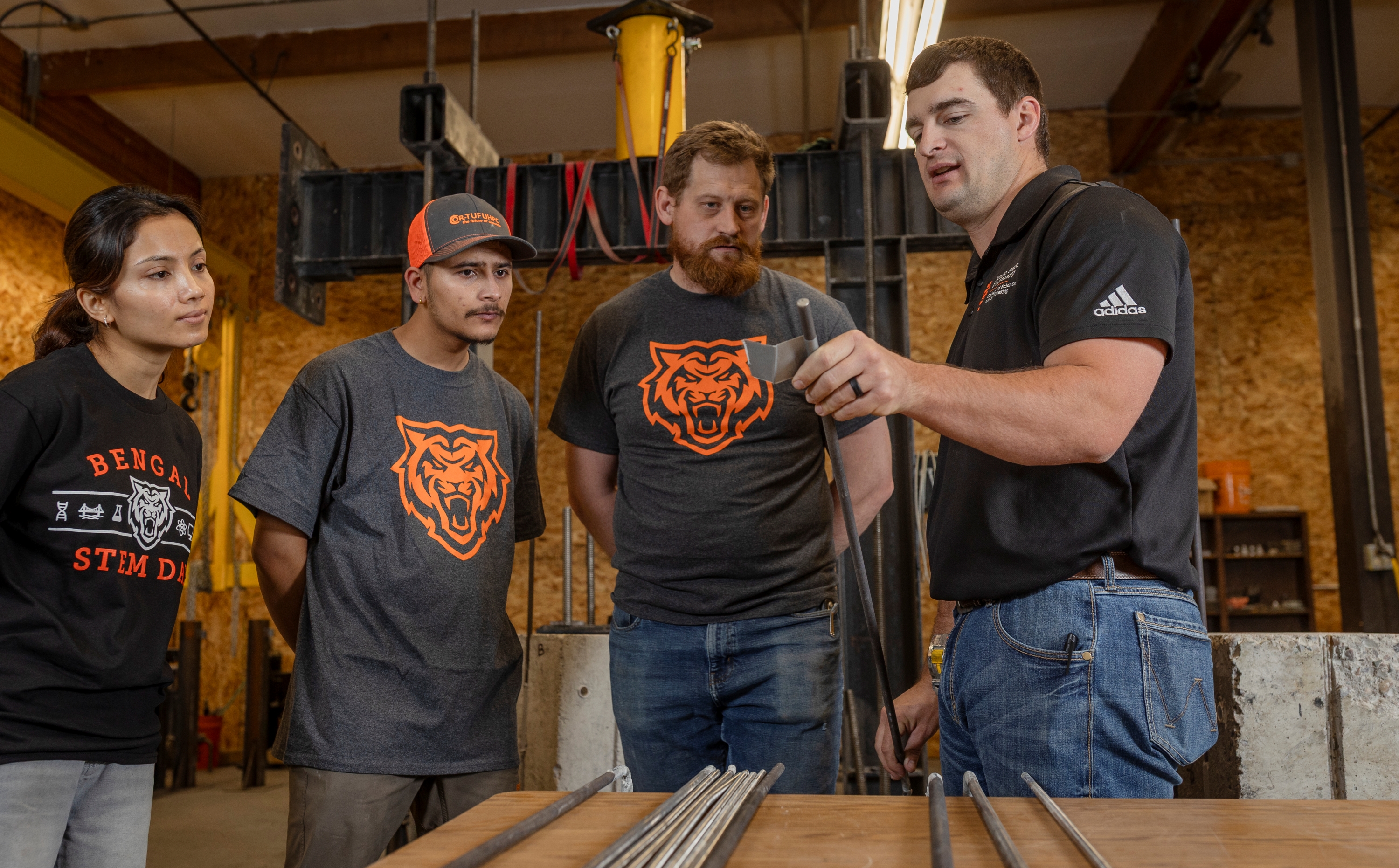 Jared Cantrell, right, explains the features of a titanium alloy bar to Prajita Budhathoki, Sujan Timsina, and Joe Shurtleff.