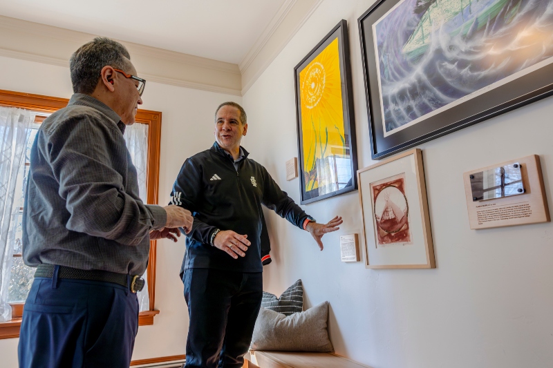 President Robert W. Wagner, Ph.D., proudly shows alumni artist Ramon Murillo how he has displayed Murillo’s art pieces in the University House.